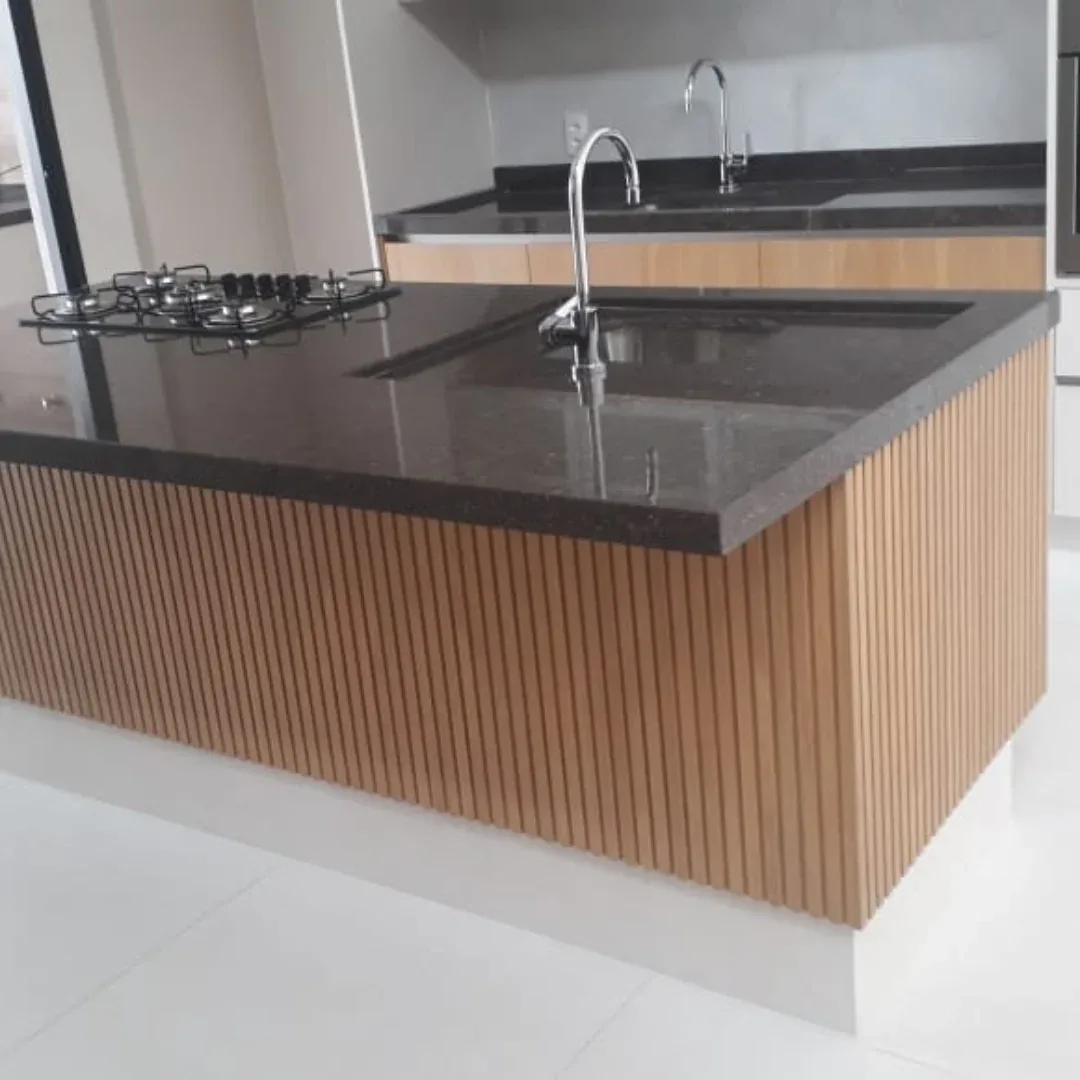 Área gourmet com bancada escura e revestimento ripado de madeira