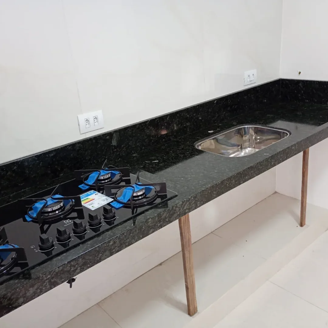 Bancada de granito escuro apoiada em pés de madeira com cooktop