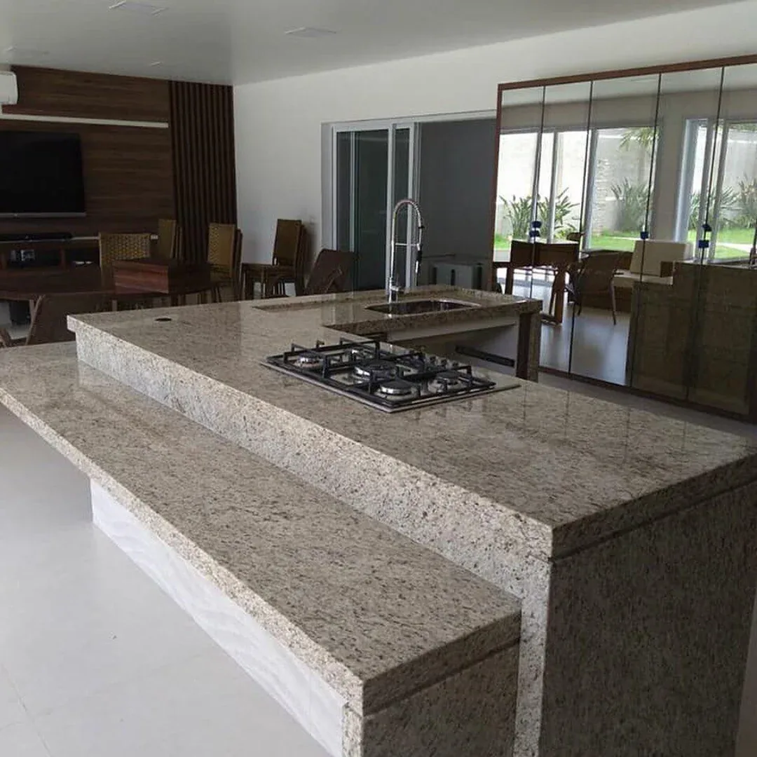 Ilha com bancada em granito claro voltada para sala de estar integrada